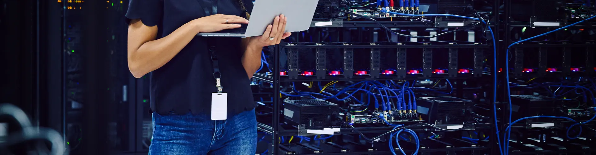 Female technician using a laptop in a server room.