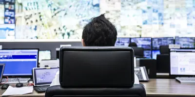 employee works in front of a wall of monitors