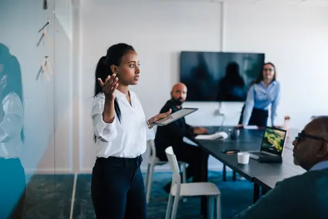 Female giving presentation to colleagues in office.