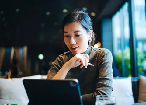 woman looking at her digital tablet while sitting at a desk