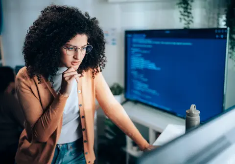 Female software engineer analyzing program code at laptop workstation