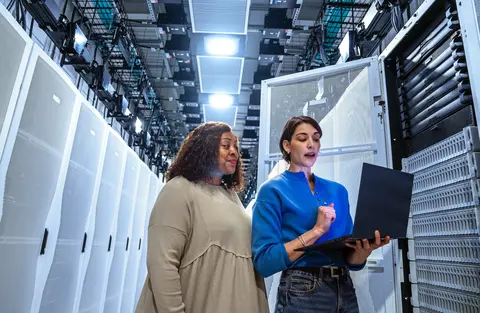 two women in data center looking at laptop