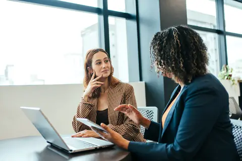 two women conversing at a desk
