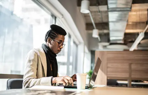 woman is sitting at a table using a laptop computer
