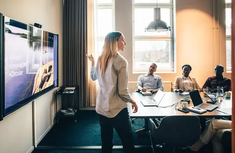 Businesswoman explaining while giving presentation to male and female colleagues in office.