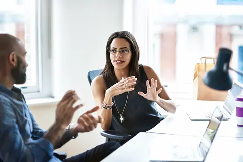 A man and a woman are sitting at a table having a conversation.