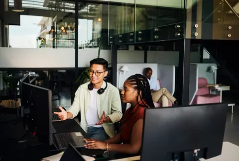 Programmers working together on a computer in office discussing a project.